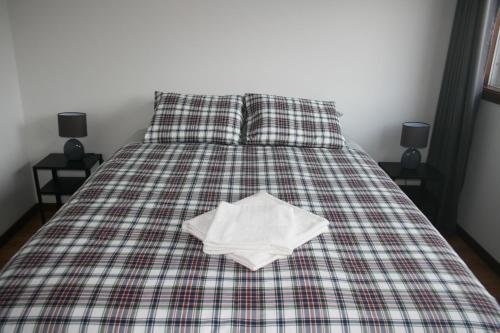 a bed with a plaid blanket with a book on it at AL das Fonsecas in Coimbra