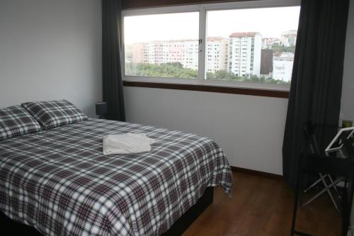 a bedroom with a bed with a plaid blanket and a window at AL das Fonsecas in Coimbra