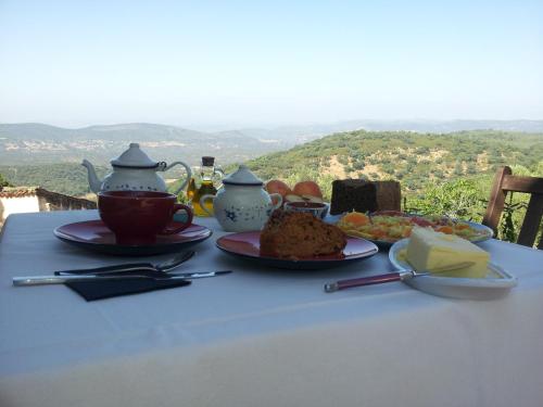 een tafel met borden eten en een kopje thee bij Alojamiento Rural Camino Beturia in Cabeza la Vaca