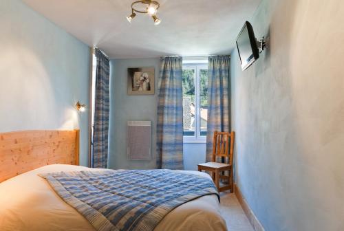 a bedroom with a bed and a tv and a window at Hôtel Restaurant Les Alpins in Saint-Julien-en-Beauchêne