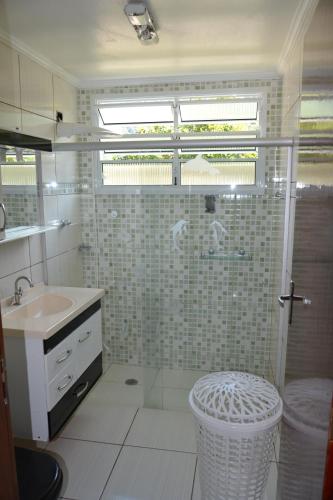 baño con lavabo y ducha con puerta de cristal en jardim das toninhas, en Ubatuba