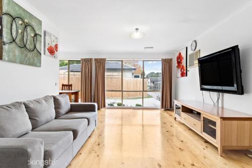 a living room with a couch and a flat screen tv at Maroondah Pet Friendly 3 Bedroom House in Kilsyth in Kilsyth