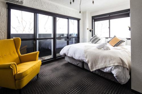a bedroom with a large bed and a yellow chair at Hotel Villa Hakuba by HHG in Hakuba