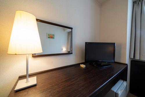 a room with a desk with a television and a lamp at Hotel S-plus Nagoya Sakae in Nagoya