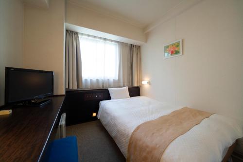 a hotel room with a bed and a flat screen tv at Hotel S-plus Nagoya Sakae in Nagoya
