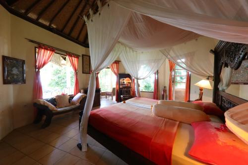 a bedroom with a large bed with a canopy at Felicianas Resort in Tejakula
