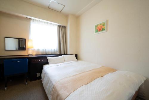 a hotel room with a bed and a desk and a window at Hotel S-plus Nagoya Sakae in Nagoya