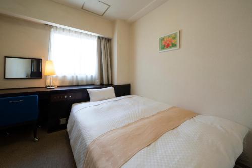 a hotel room with a bed and a desk and a television at Hotel S-plus Nagoya Sakae in Nagoya
