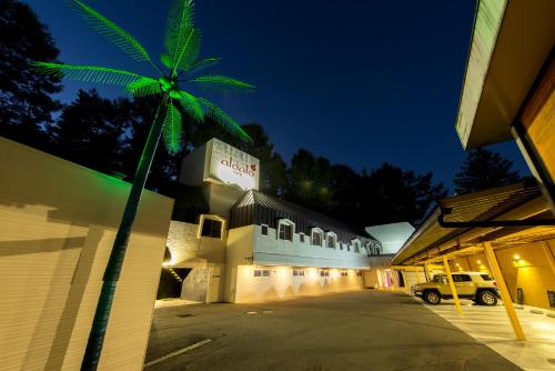 a palm tree in front of a building at night at aloalo in Fujikawaguchiko