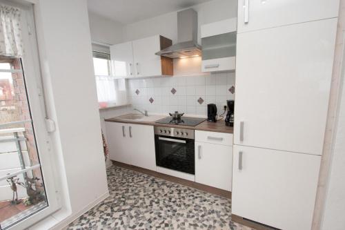 a kitchen with white cabinets and a stove at 50040 FeWo kleine Nordseeliebe in Altfunnixsiel