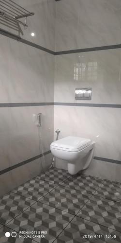 a white toilet in a bathroom with a tiled floor at Nandana's Residency Munnar - A 4BHK Homestay for Indian Families in Munnar