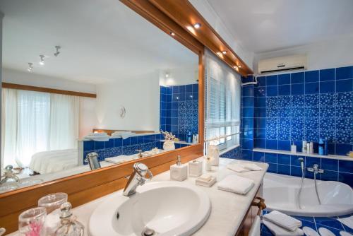 a bathroom with a sink and a tub and a mirror at Unique house by the sea in Paralía Proastíou