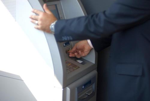 a man is putting his hand in an atm machine at Ramada by Wyndham Oradea in Oradea