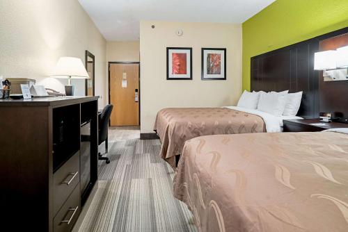 a hotel room with two beds and a desk at Quality Inn & Suites in Robbinsville