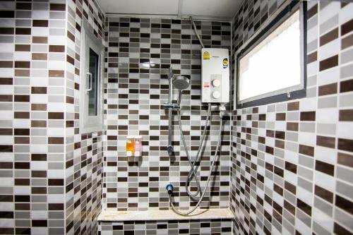 a bathroom with a shower with black and white tiles at Regent Ngamwongwan Hotel in Nonthaburi