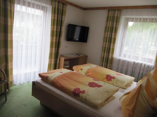 a bedroom with two beds and a flat screen tv at Gästehaus Luxner in Strass im Zillertal