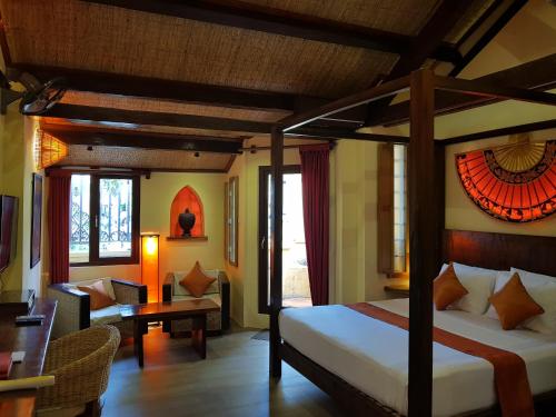 a bedroom with a canopy bed and a living room at Rikitikitavi in Kampot