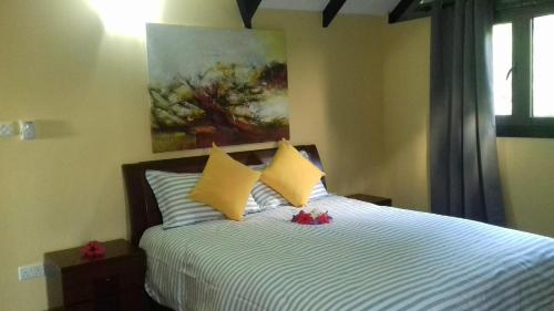 a bedroom with a bed with yellow pillows and a painting at SHAY LYAH SELF CATERING in Victoria