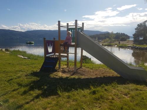 un bambino seduto su uno scivolo in un parco giochi di Utvika Camping a Nes