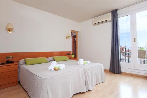 a bedroom with a bed with white sheets and a window at Hotel Everest in Barcelona