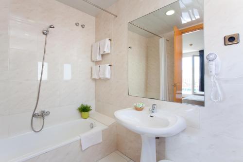 a white bathroom with a sink and a tub and a mirror at Hotel Everest in Barcelona