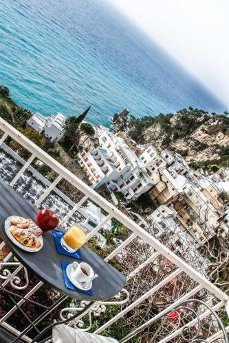 a table with a plate of food next to the ocean at Positano Art Hotel Pasitea in Positano
