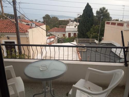a balcony with a table and chairs and a view at Captain's Rooms in Aegina Town
