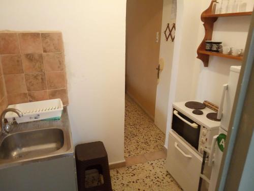 a small kitchen with a sink and a stove at Captain's Rooms in Aegina Town