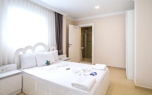 a white bedroom with a large white bed with towels on it at White Star Antalya in Antalya