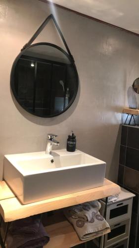 une salle de bain avec un lavabo blanc et un miroir dans l'établissement Chambre et Table d'hôtes Magaadjukalo, à Saint-Maurice-de-Lignon