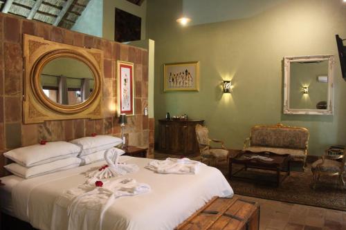 a bedroom with a bed with a mirror and a chair at Misty Hills Country Hotel, Conference Centre & Spa in Muldersdrift