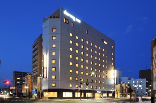 a tall gray building on a city street at night at Dormy Inn Morioka in Morioka