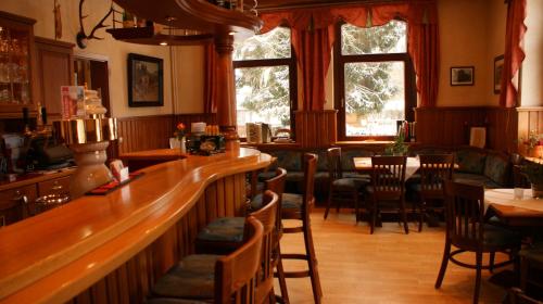 a restaurant with a bar and a table and chairs at LandHotel Lönskrug in Hellental