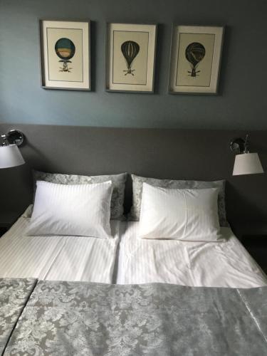 ein Bett mit zwei Kissen und zwei Bildern an der Wand in der Unterkunft Destine in Rogoznica