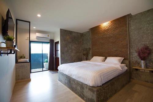 a bedroom with a large bed with a brick wall at Pimchanok Resort in Phetchaburi