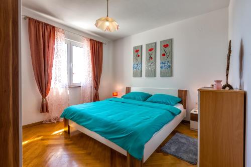 a bedroom with a large bed with a blue blanket at Apartments Kira, Mali Lošinj in Mali Lošinj