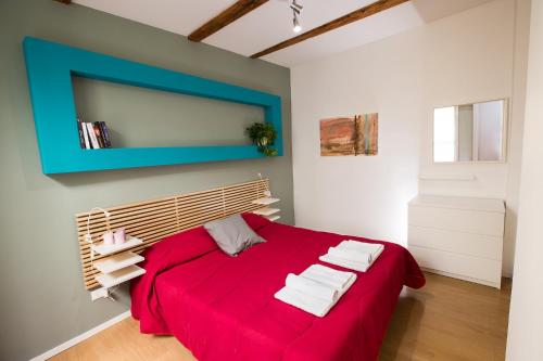 sypialnia z czerwonym łóżkiem i ręcznikami w obiekcie Guasto Apartment w Bolonii