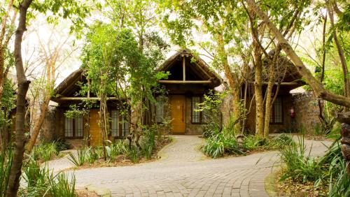 a house in the middle of a forest with trees at Misty Hills Country Hotel, Conference Centre & Spa in Muldersdrift
