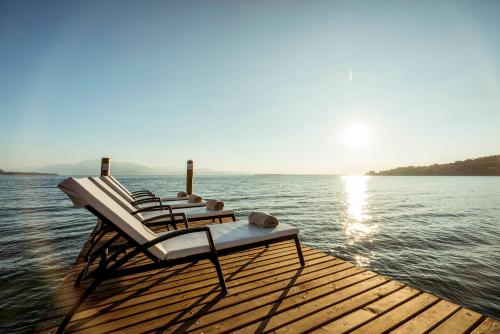 a group of chairs sitting on a dock on the water at Splendido Bay Luxury Spa Resort in Padenghe sul Garda