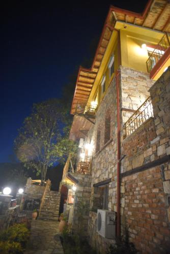 un edificio in pietra con luci accese di notte di Santa Marina Guesthouse a Kato Loutraki