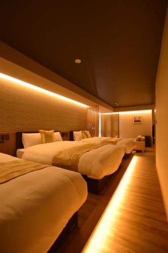 two beds in a hotel room with lights at GRAND BASE Beppu Ekimae in Beppu