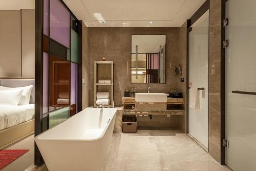 a bathroom with a tub and a bed and a sink at Tianyuan Grand Hotel Xiamen in Xiamen
