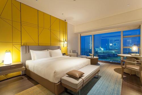a bedroom with a large bed with a yellow wall at Tianyuan Grand Hotel Xiamen in Xiamen