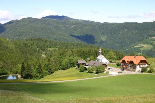 an aerial view of a house on a hill with a church at Alpengasthof Moser in Karchau
