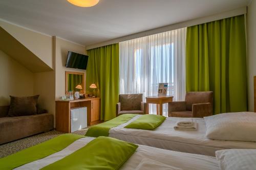 Hotel ***NAT Sarbinowo في ساربينوفو: سريرين في غرفة الفندق مع ستائر خضراء