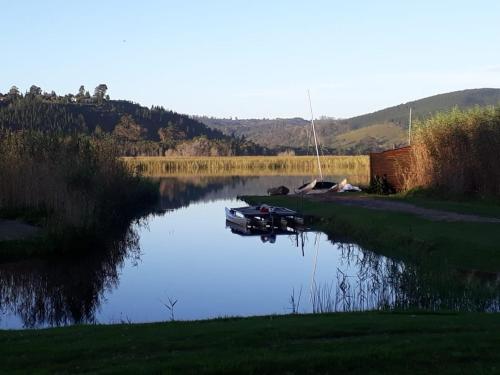 
a boat sitting on the side of a river next to a body of water at Bushbuck Camp in Sedgefield
