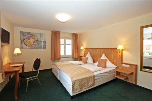 ヴェストハウゼンにあるHotel Restaurant Adlerのベッドとデスクが備わるホテルルームです。