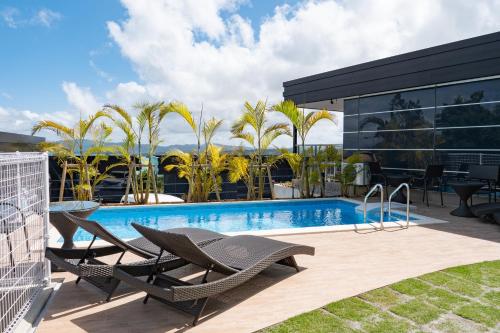 a swimming pool with two chairs next to a building at One Suite THE TERRACE in Nakijin
