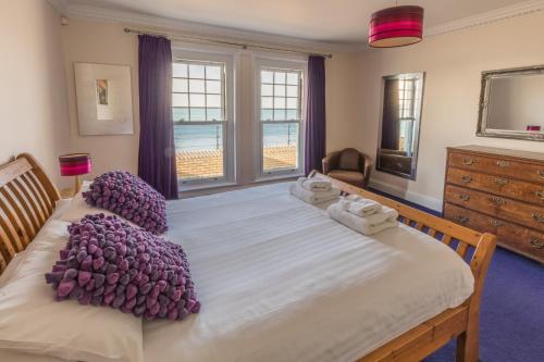 1 dormitorio con 1 cama grande con almohadas moradas en Promenade Apartment with own Beach Hut en Totland