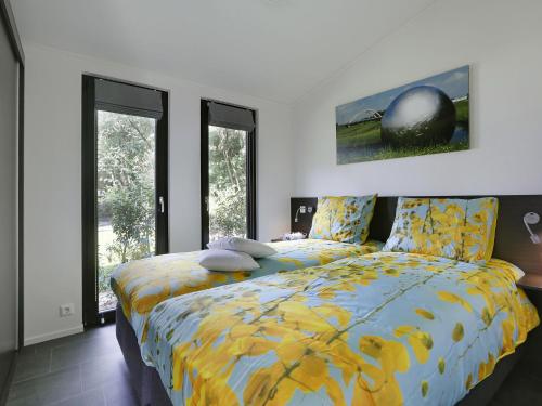 a bedroom with a bed with a yellow comforter at Wellness Forest Retreat in Markelo
